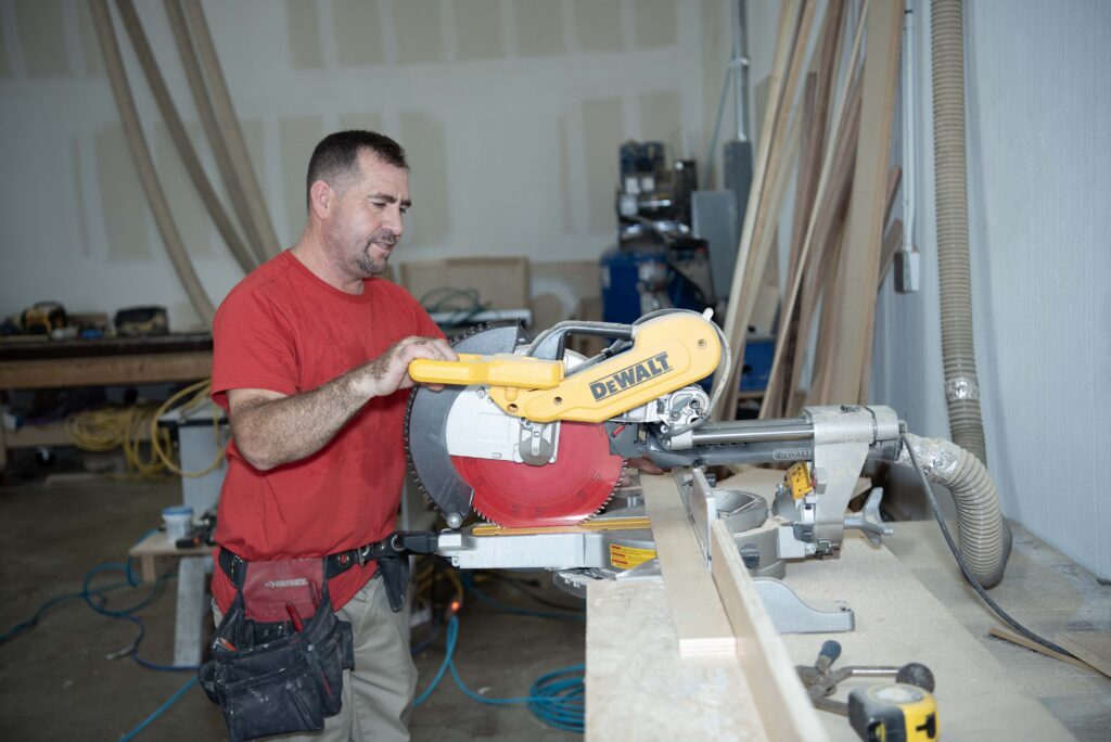 Skilled carpenter cutting lumber with miter saw during residential reconstruction project